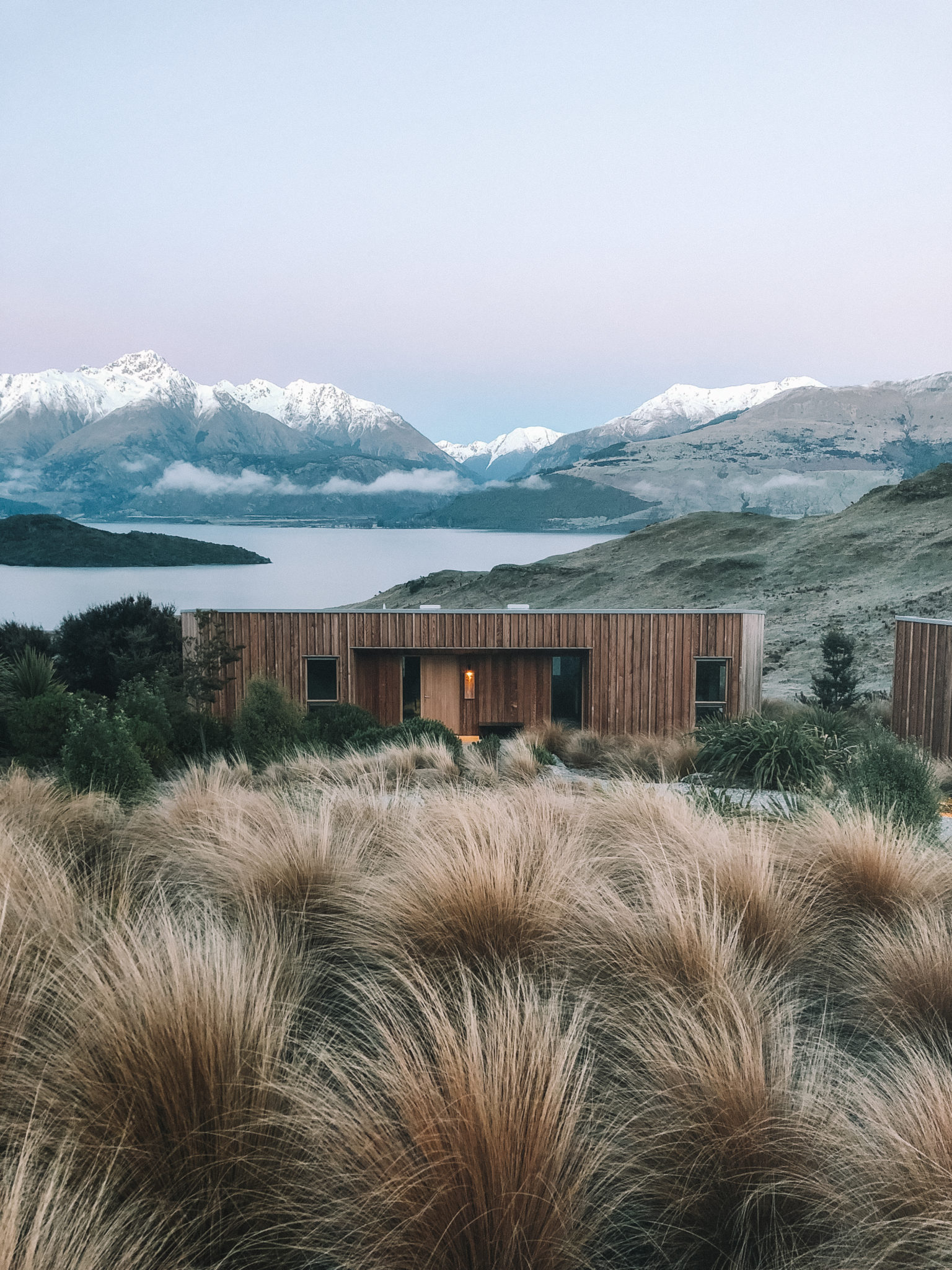 Aro Hā timber lodges among tussock grass with mountain views