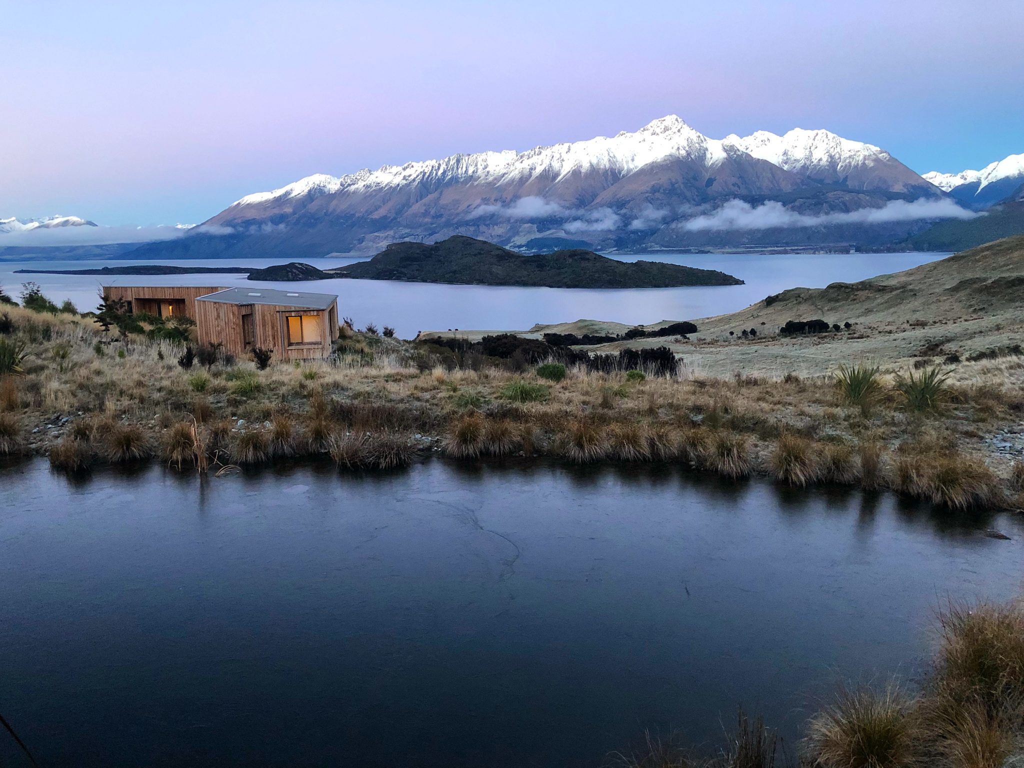 Morning light over the tarn and snow-capped mountains at Aro Hā